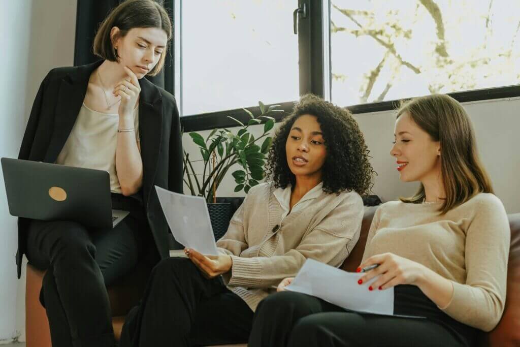 Three professional women engaged in a collaborative meeting in a modern office setting.